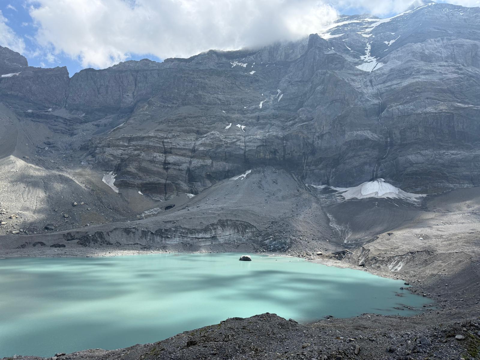 Griesslisee am Klausenpass mit Felswänden, Schutt und verbliebenen Schneefeldern im August