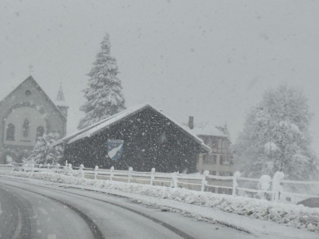 Starker Schneefall in einem Dorf mit verschneiter Strasse, Häusern und Kirche im Winter 2025/26