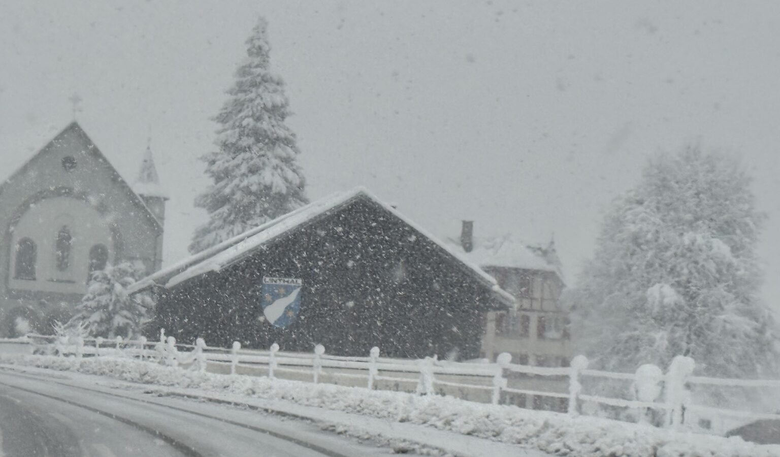 Starker Schneefall in einem Dorf mit verschneiter Strasse, Häusern und Kirche im Winter 2025/26
