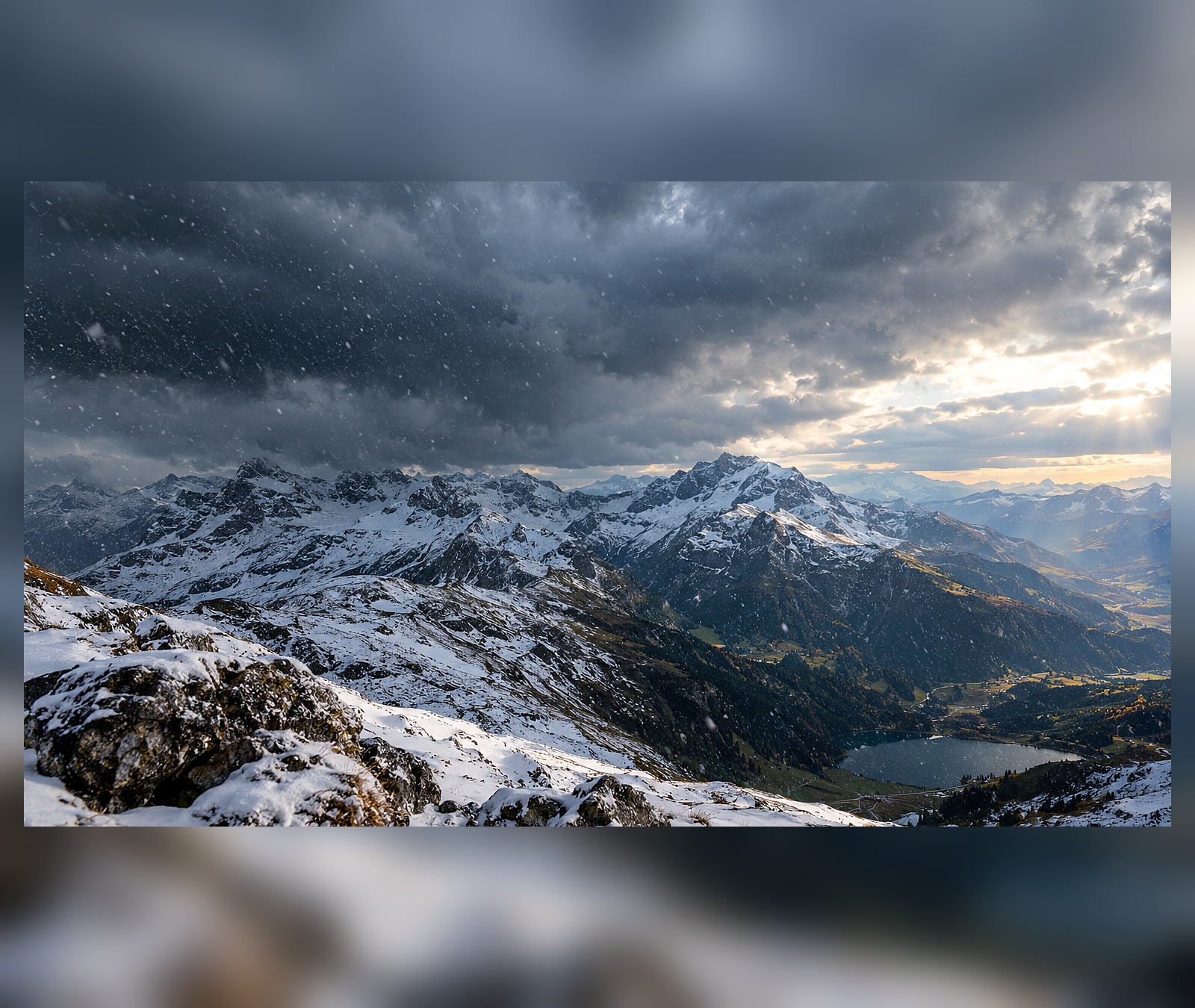 Frischer Schnee auf hohen Alpengipfeln unter dunklen Wolken